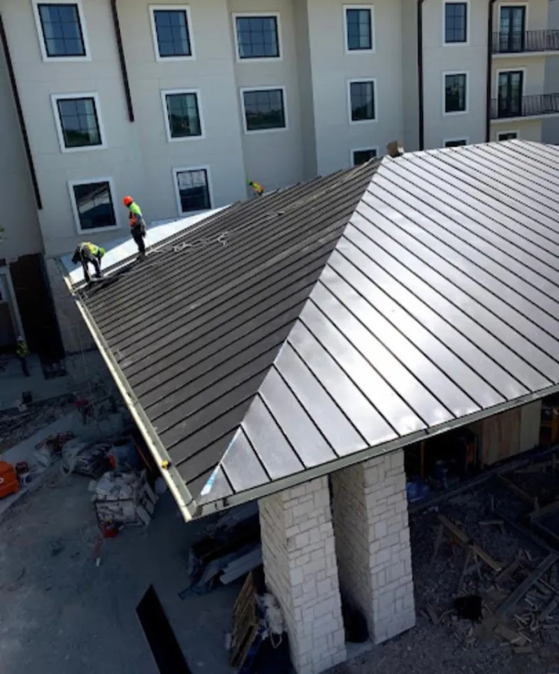 Crew installing standing seam metal roof panels on a commercial project in Wellston